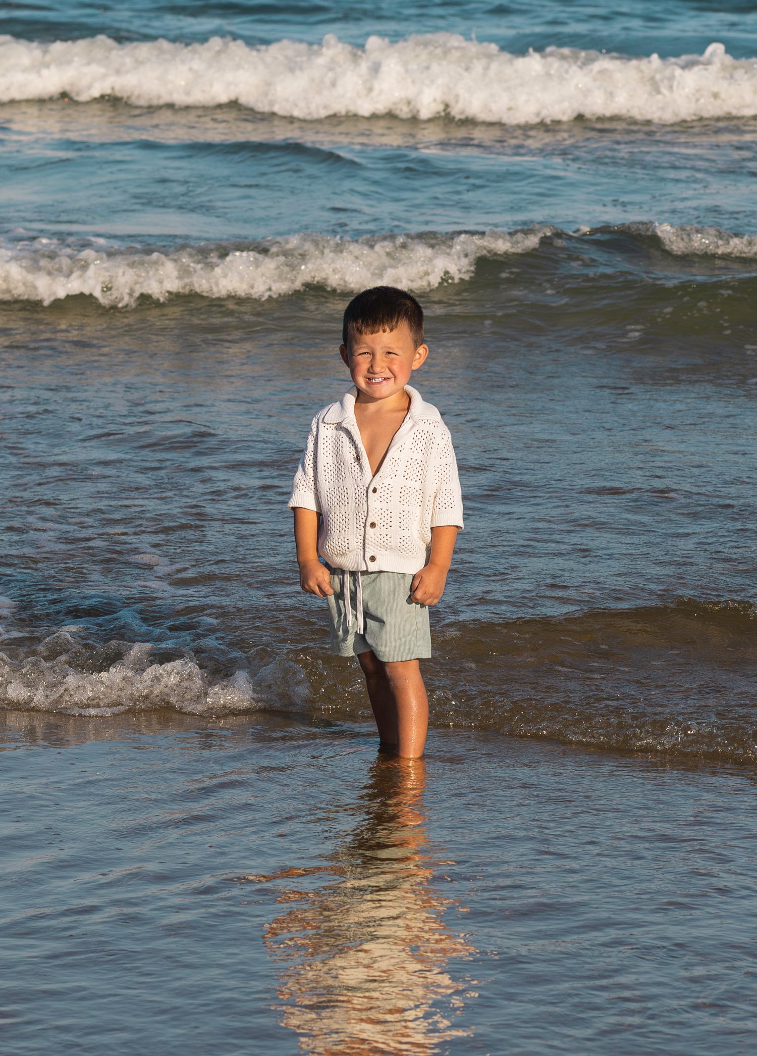 Young boy standing by the water
