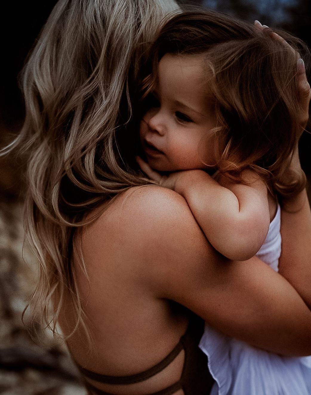 Tender moment of a mother embracing her young toddler child in a warm hug.