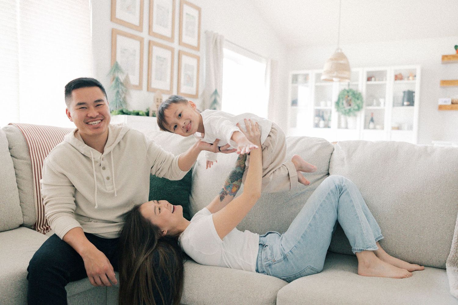Joyful family playing and lounging together on a comfortable grey couch in a bright, modern living room.