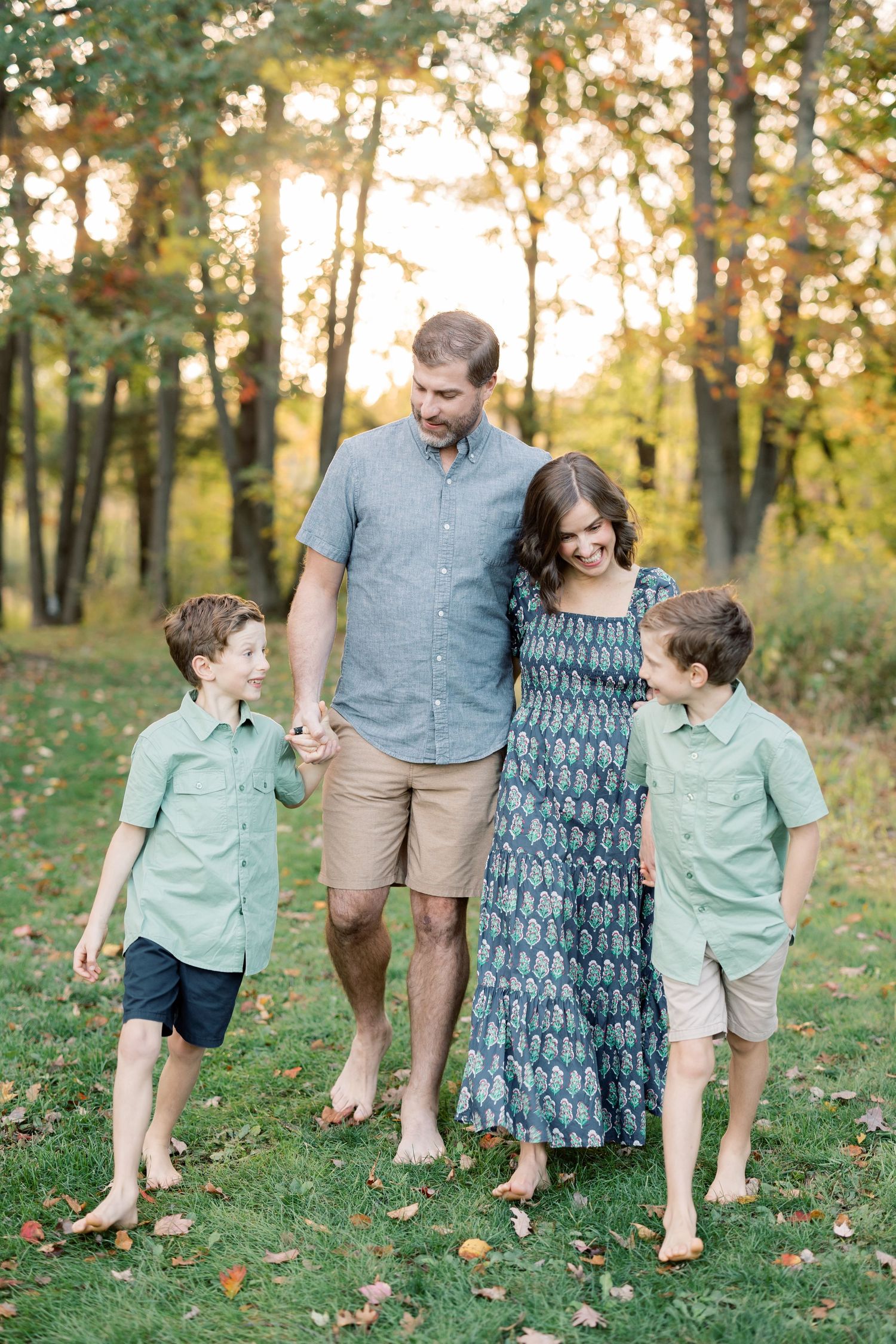 Family walking together and playing in a grassy park during golden hour sunset.