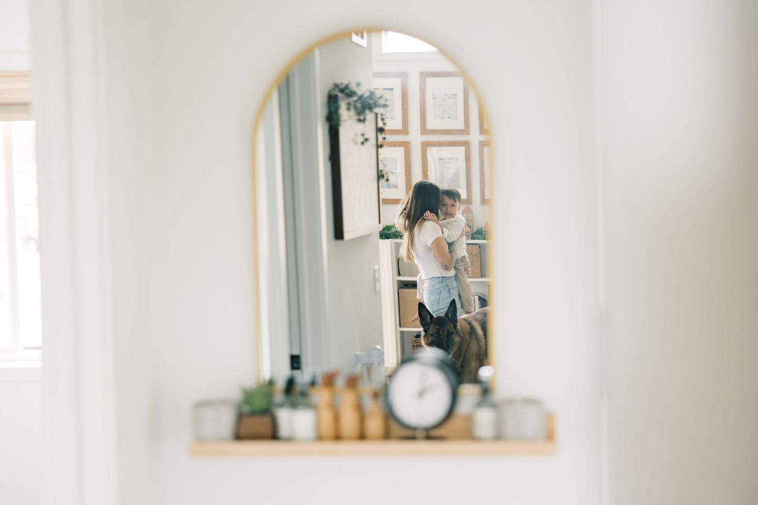 A vintage-inspired mirror reflection shows an arched frame with decorative items and a small clock on the ledge.