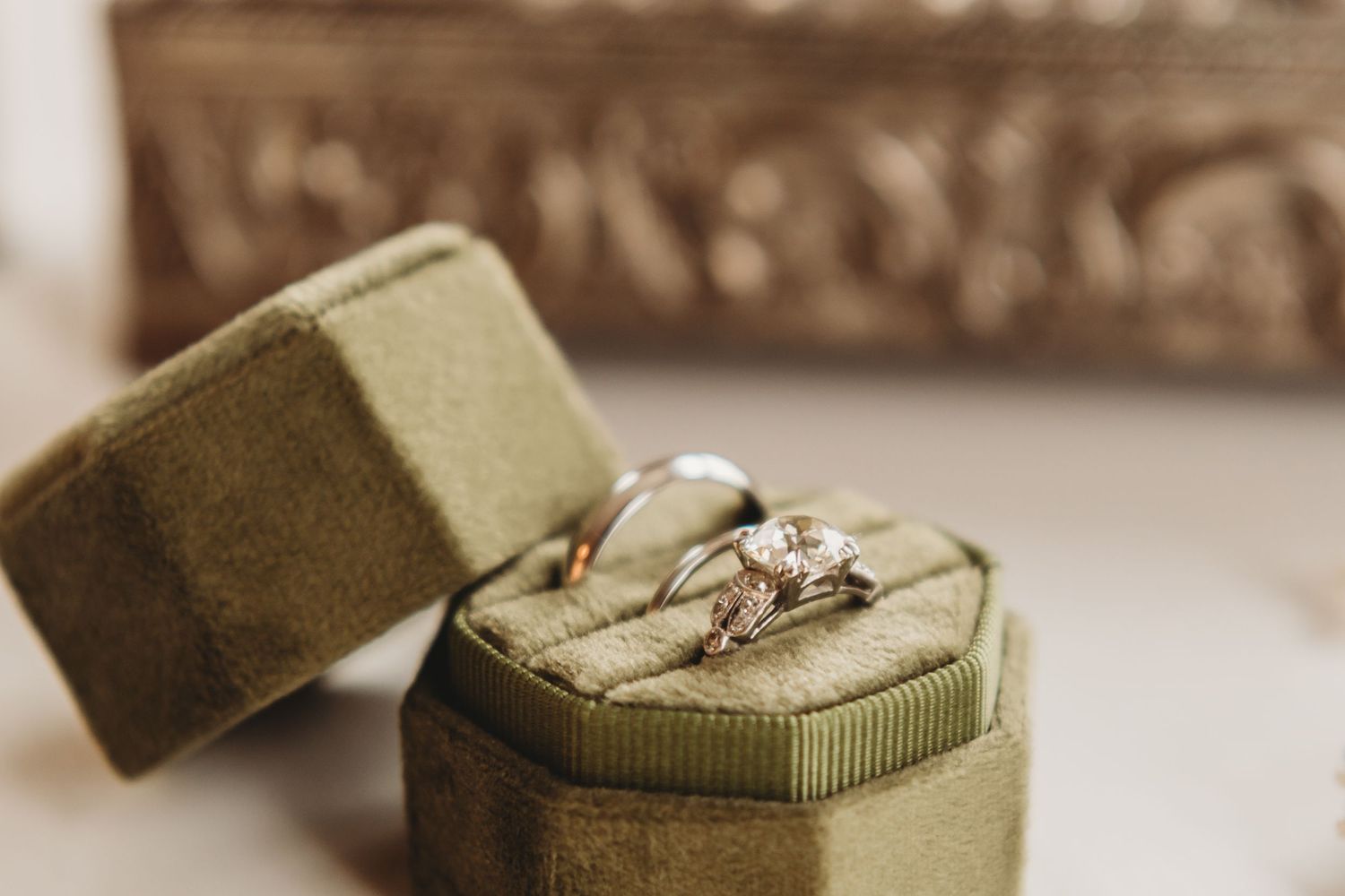 Diamond engagement ring and wedding band displayed in open green velvet ring box close-up.