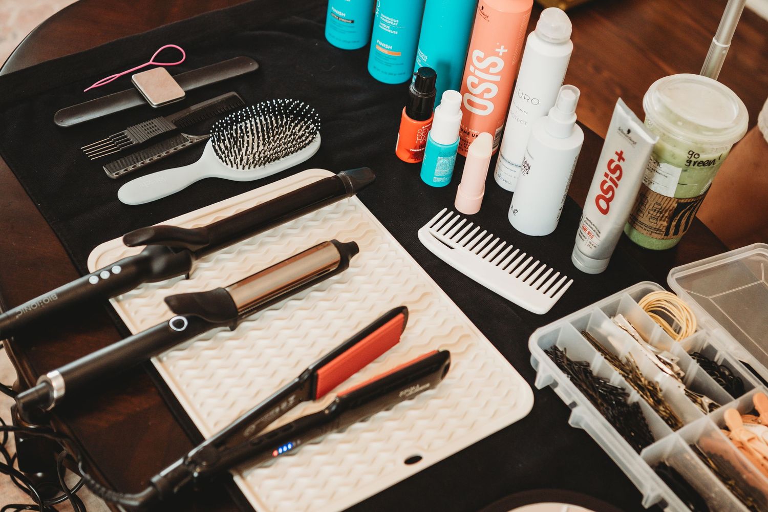 Professional hair styling tools, combs, and OSIS products arranged on dark surface.