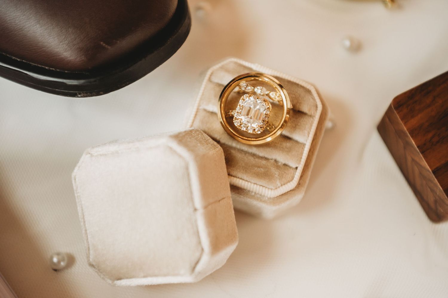 Gold engagement ring with emerald cut diamond displayed in a velvet ring box on a white surface.