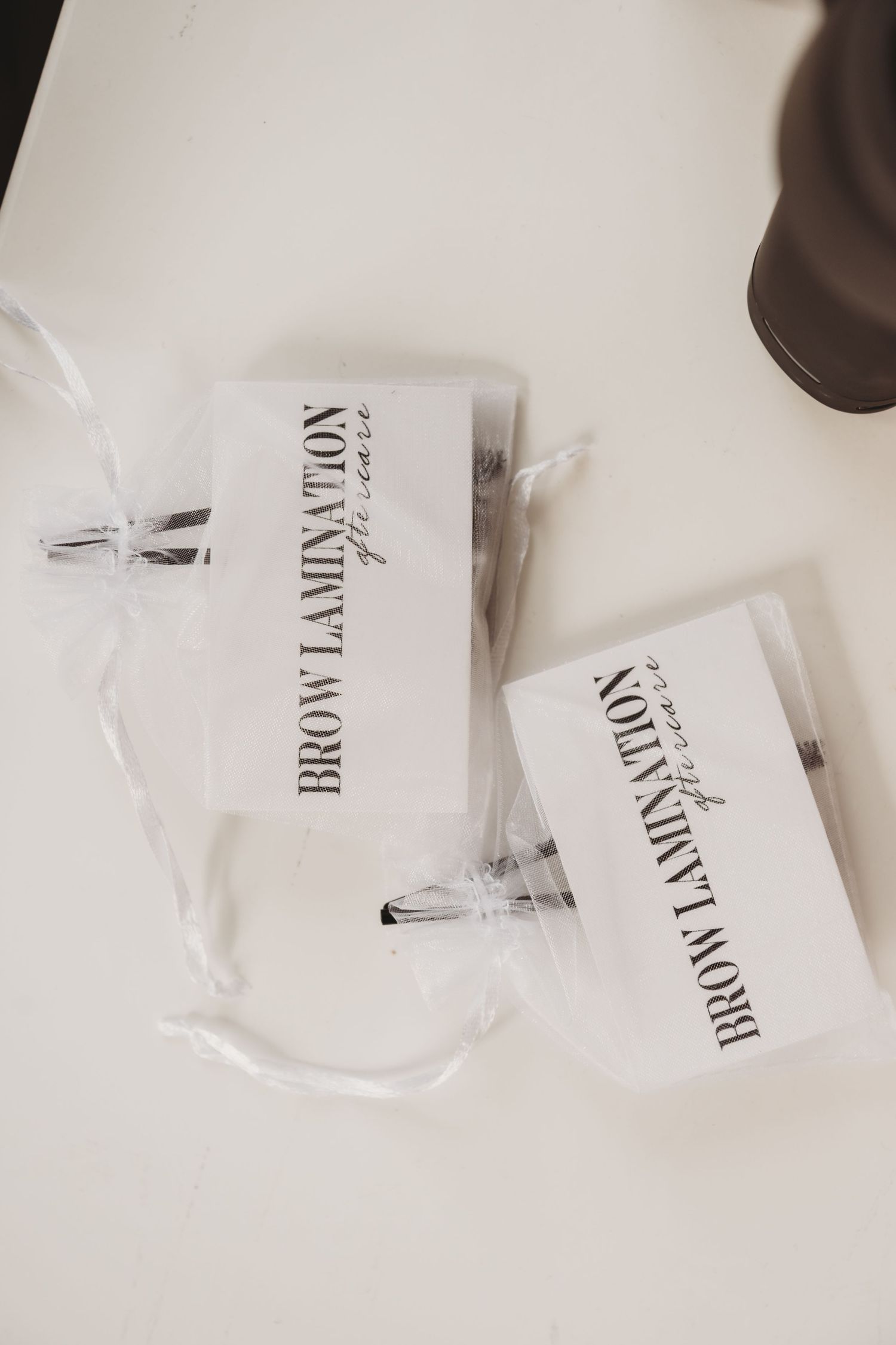 Two brow lamination aftercare kit packets displayed on a white surface.