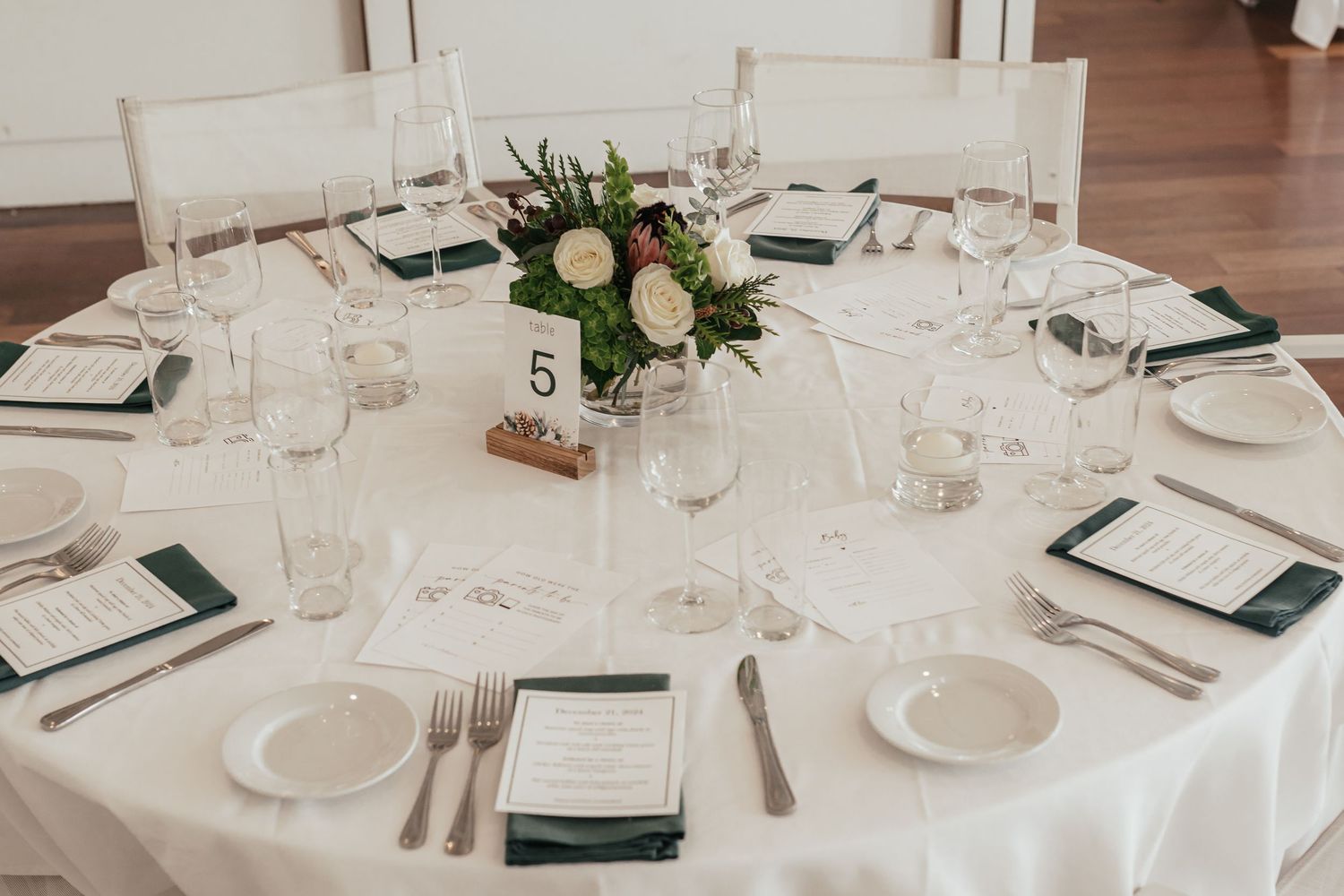 Elegant wedding reception table set with white linens, floral centerpiece, and place settings.