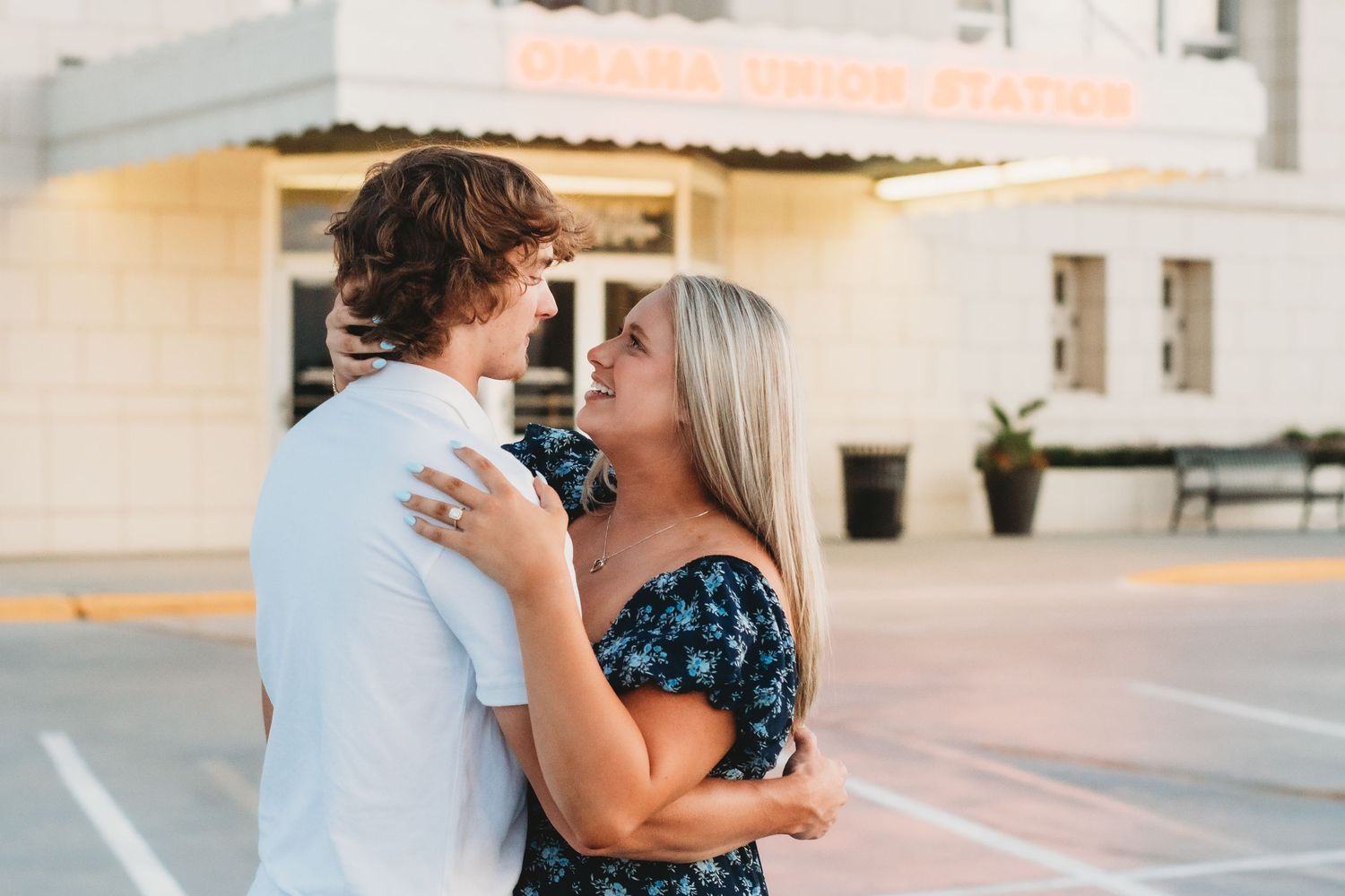 Happy couple embracing and smiling at each other outside an Omaha Union Station building at sunset.