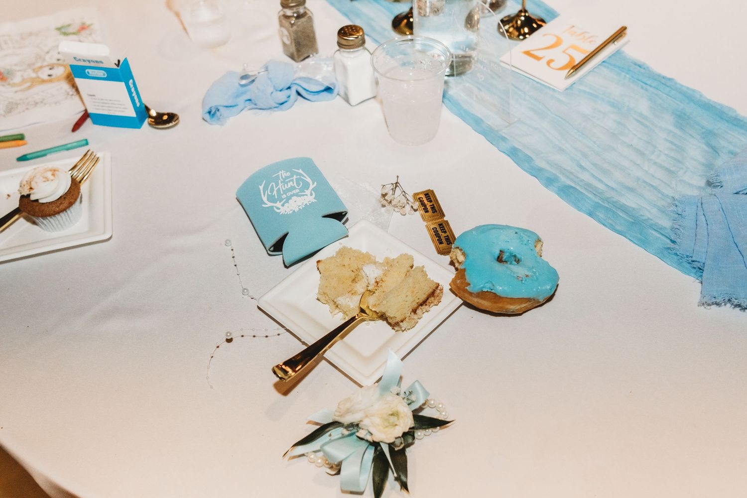 Wedding reception table with blue geode cake server, koozie, and floral centerpiece details.