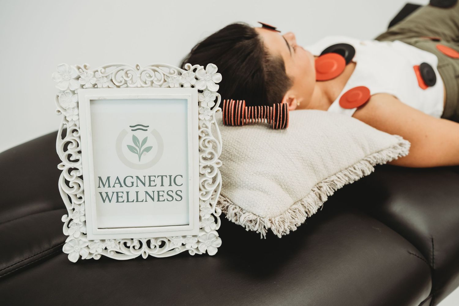 Woman relaxing on massage table with magnetic therapy devices at Magnetic Wellness spa treatment session.