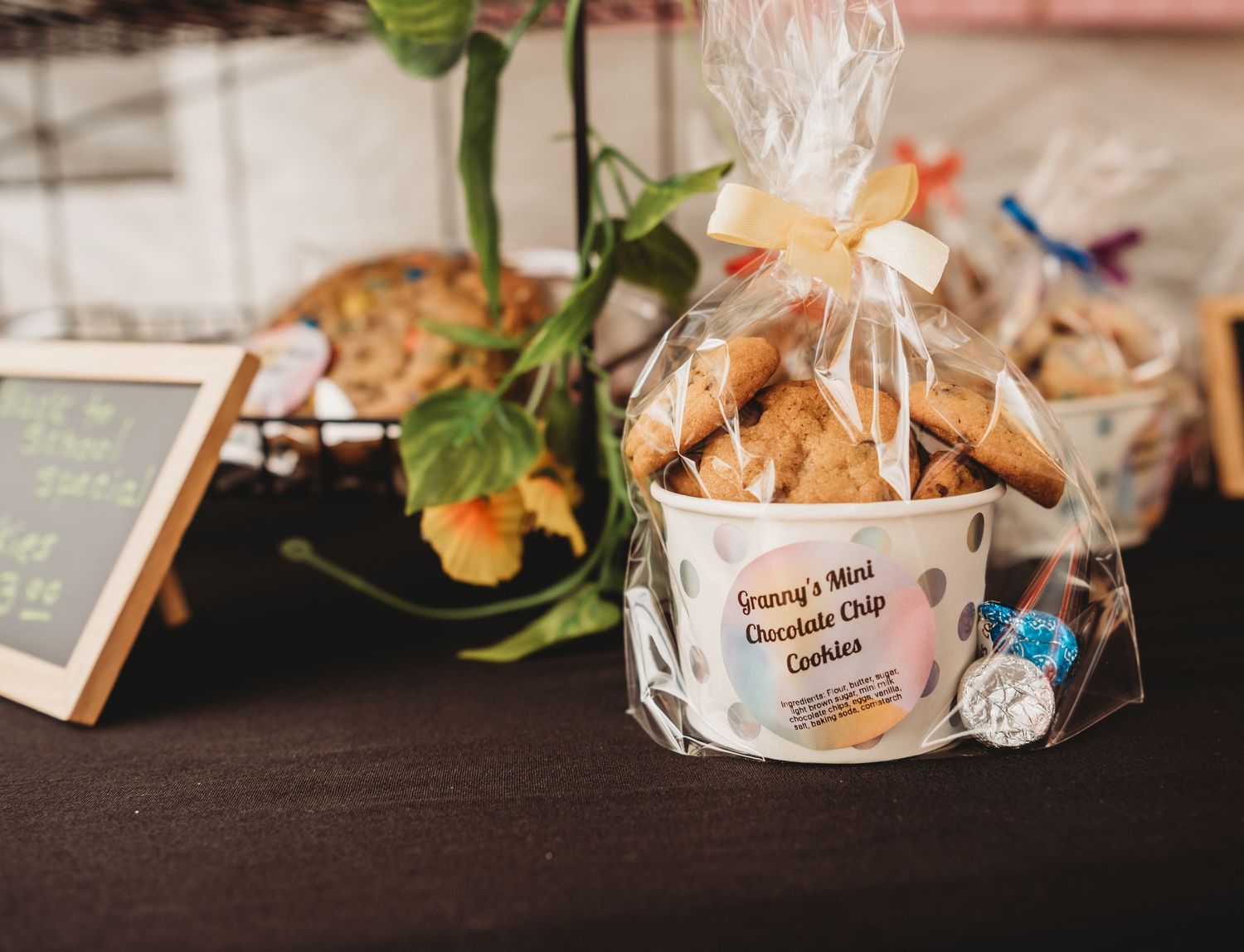 Granny's Mini Chocolate Chip Cookies in a polka dot tin with cellophane wrap and bow on a dark table.