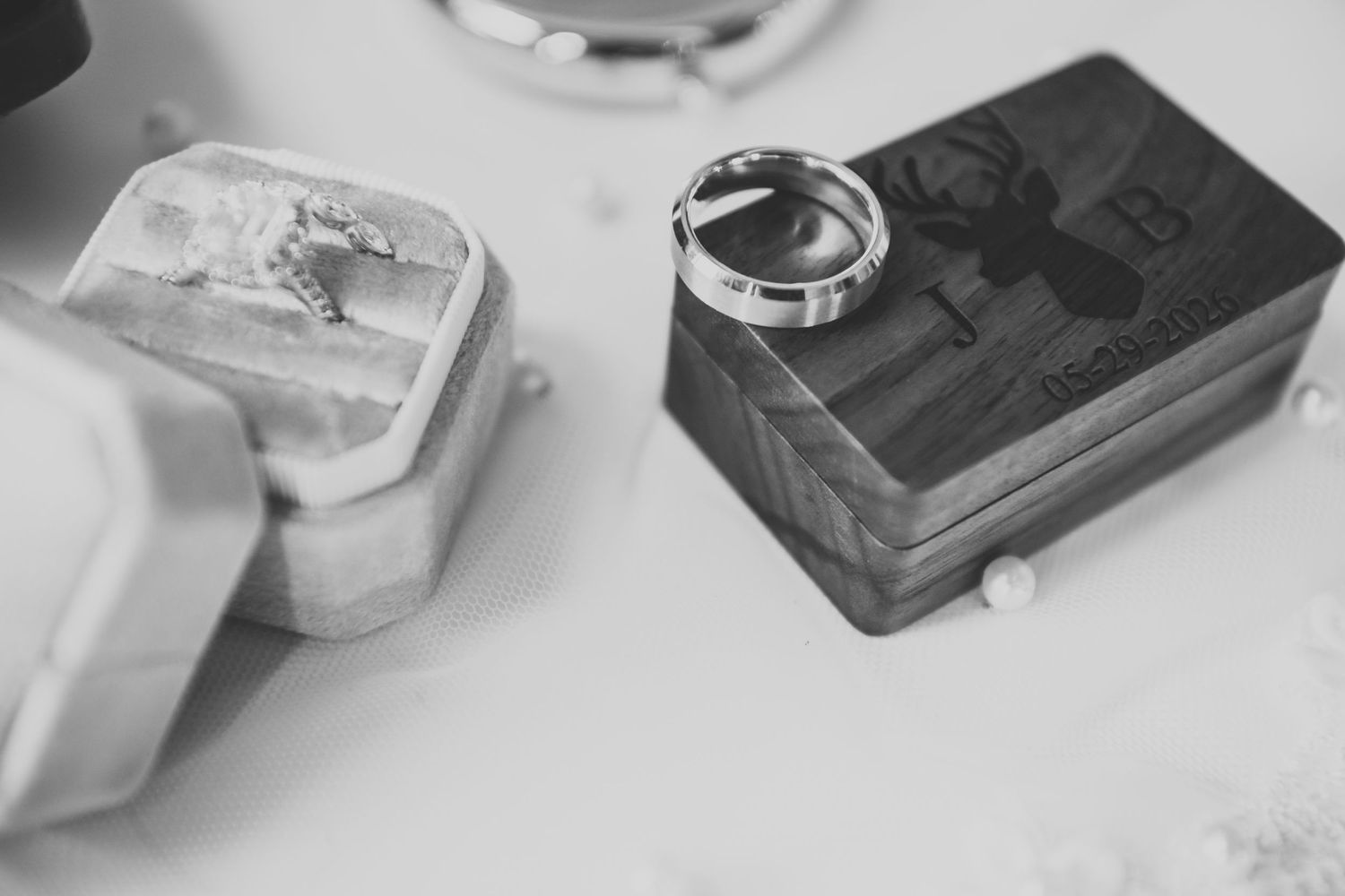 Black and white photo of wedding rings resting on decorative keepsake boxes.