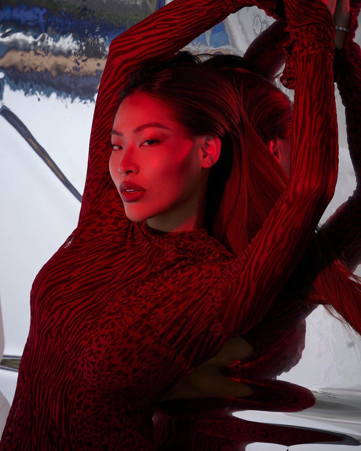 Model in a red textured bodysuit posed dramatically under red lighting.