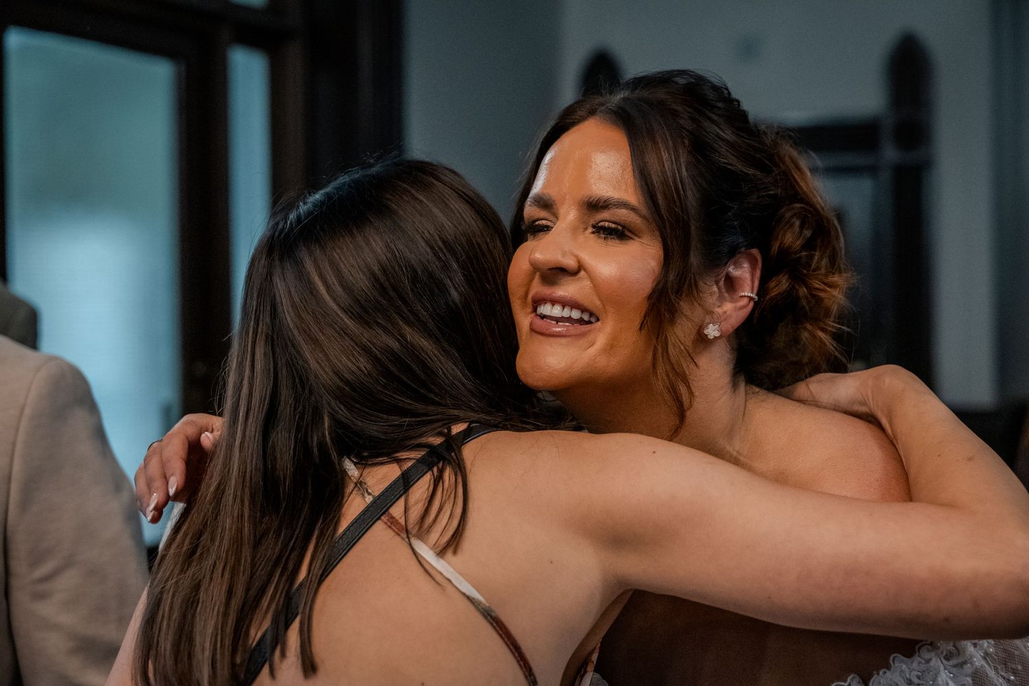 Smiling bride sharing an emotional hug with a guest during the wedding celebrations.
