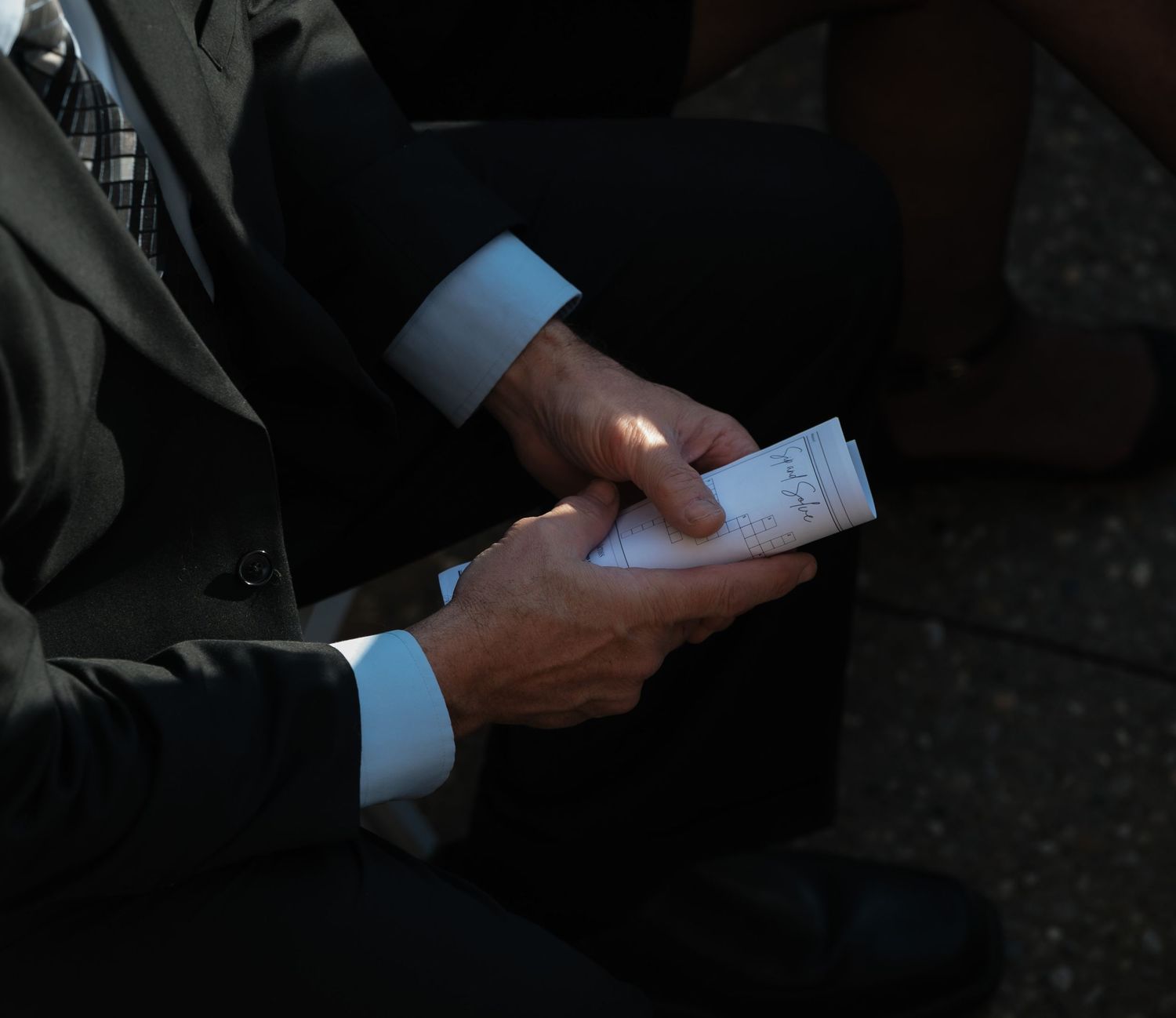 Close-up sequence of hands holding and examining a small paper card or document in dim lighting.
