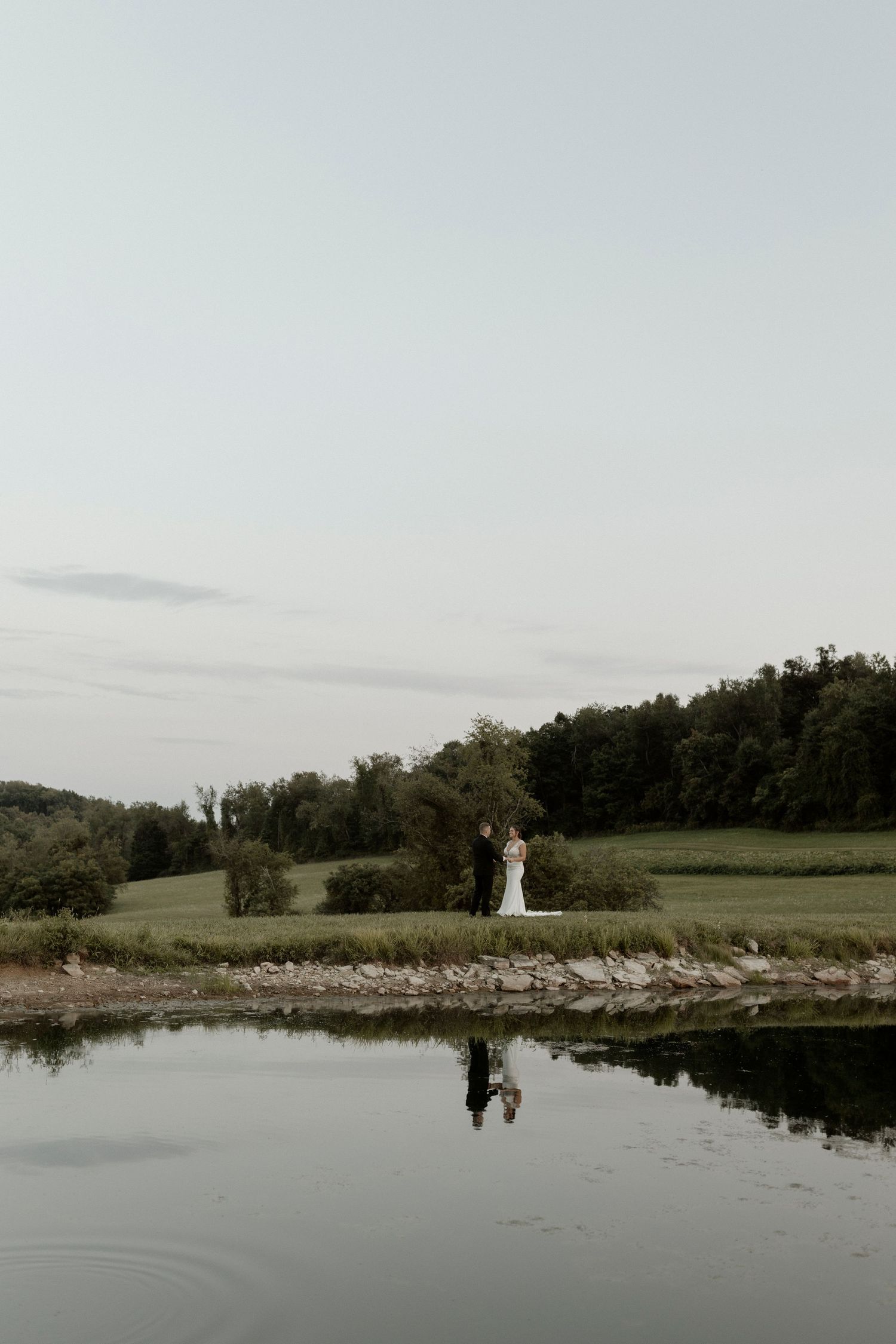 Tranquil pond reflects the surrounding green landscape on a cloudy day at a scenic country venue.