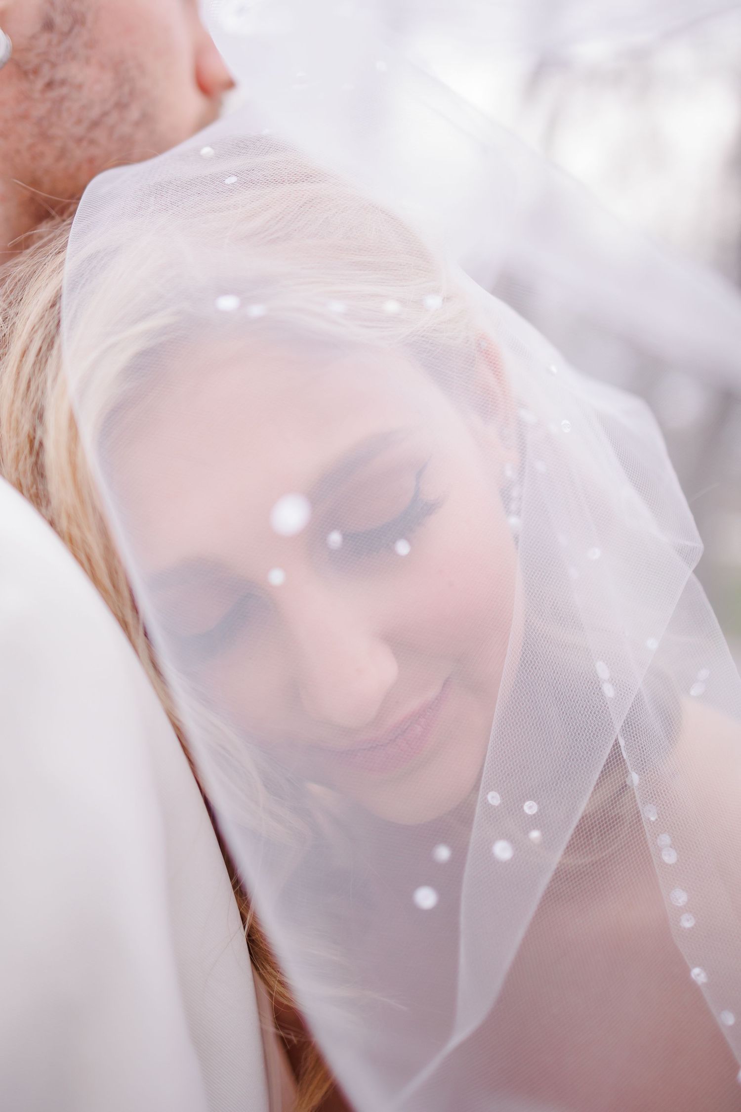 Romantic moment captured through a sheer white veil with soft lighting.