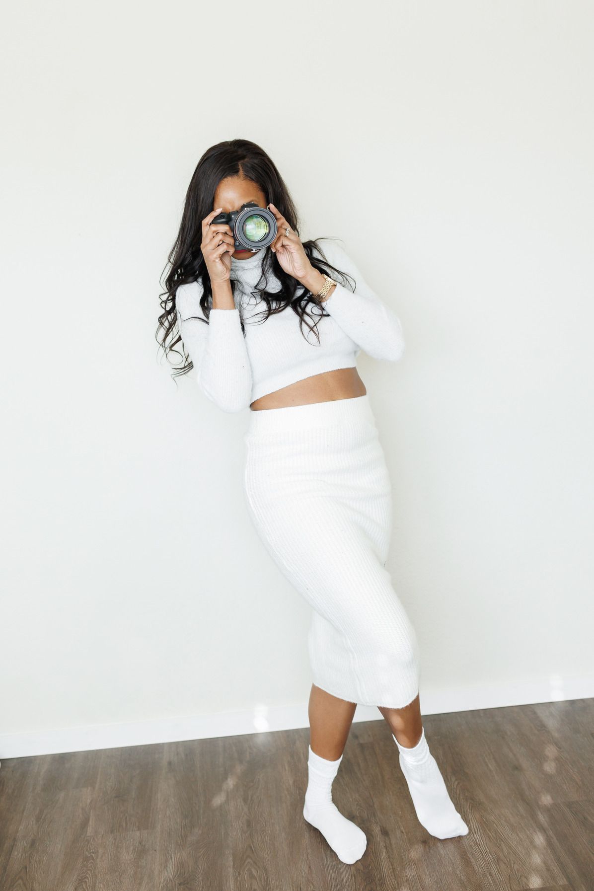 Professional photographer wearing all white outfit taking photo with camera.