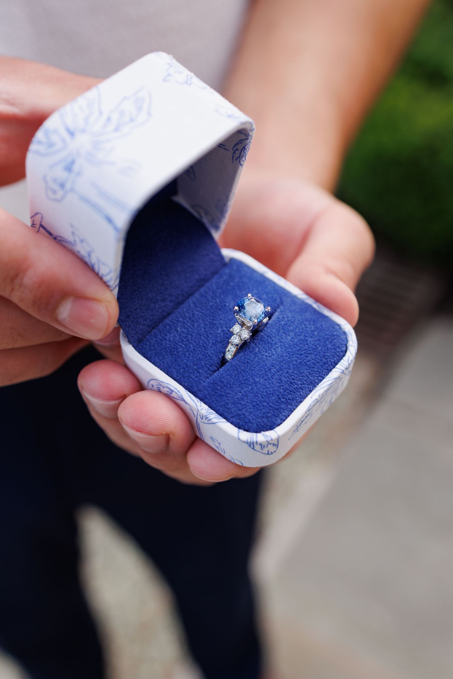 A series of photos showing a small blue ring box being opened to reveal a sparkling diamond engagement ring.