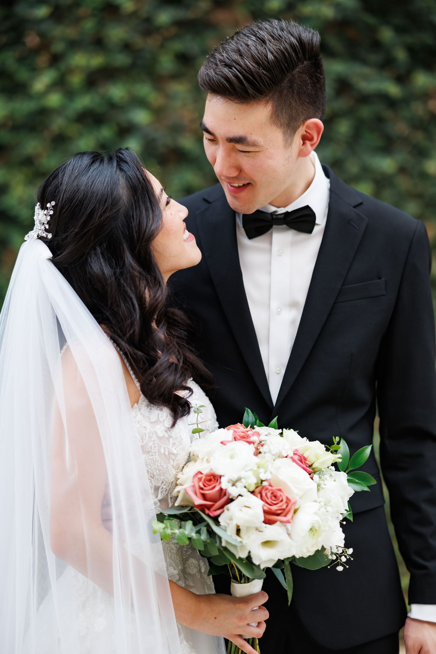 Romantic outdoor portrait with bride holding bouquet of pink and white roses.