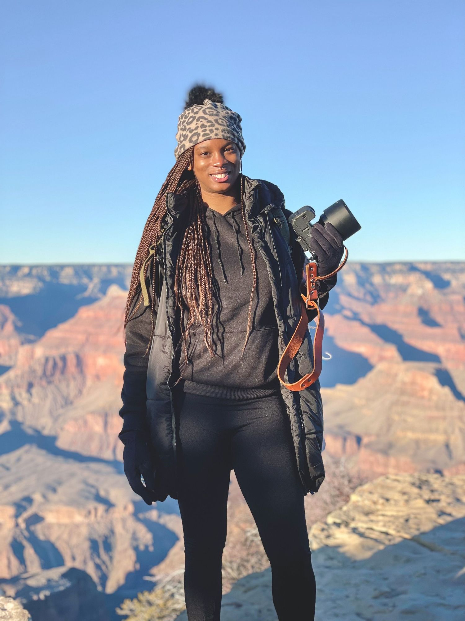 Photographer in dark clothing captures scenic views of the Grand Canyon's majestic cliffs during golden hour.