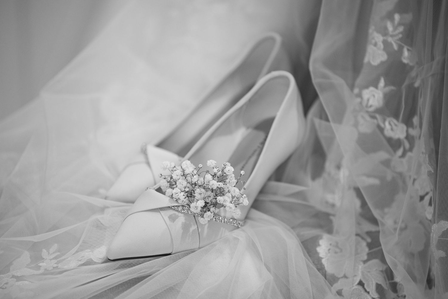 A collection of elegant wedding dress details showing lace, beading, and fabric textures in black and white photography.