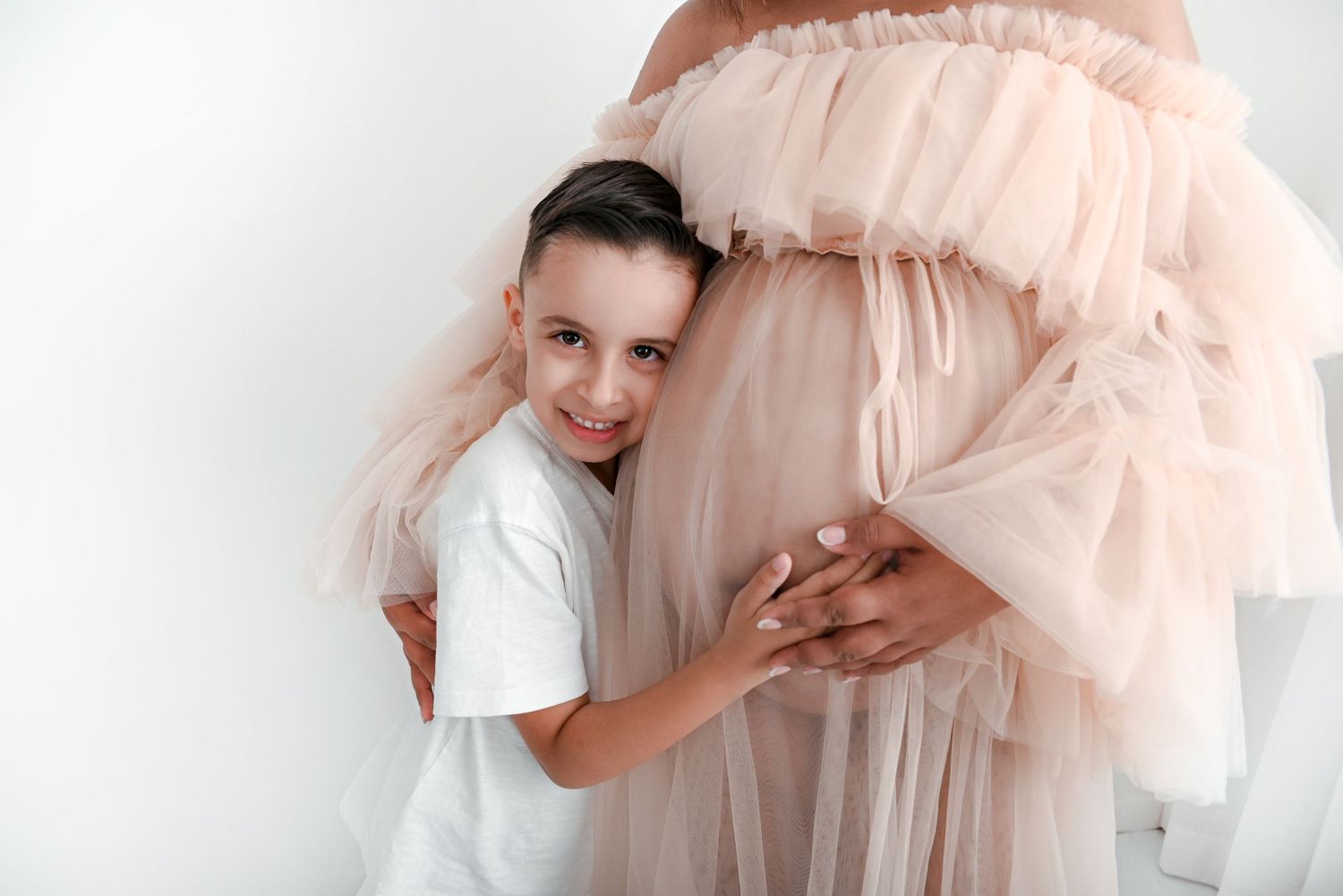 Gentle embrace of a tulle dress in soft pink tones against white background.