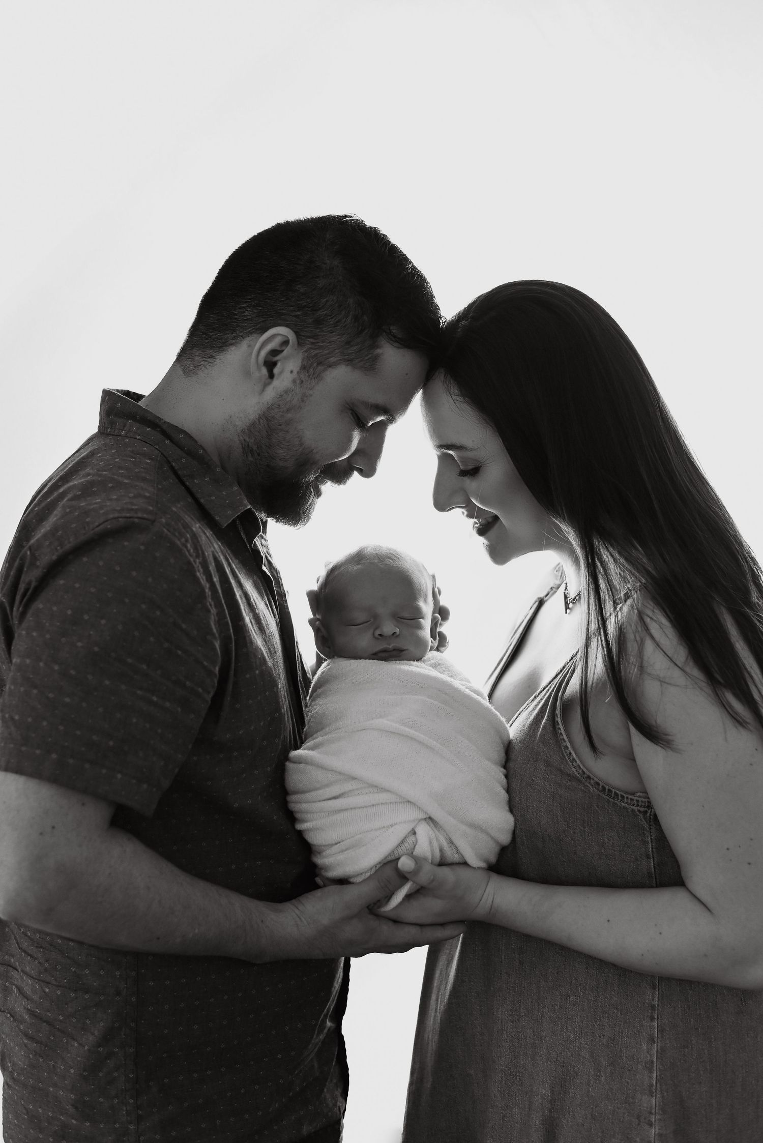 Artistic black and white portrait of a tender family moment against light background.