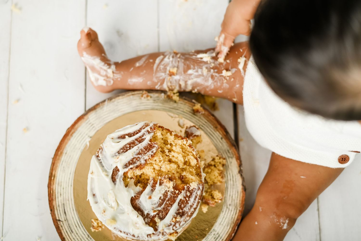 Hands mixing ingredients in a metal mixing bowl with gold accents and decorative patterns on a white surface.