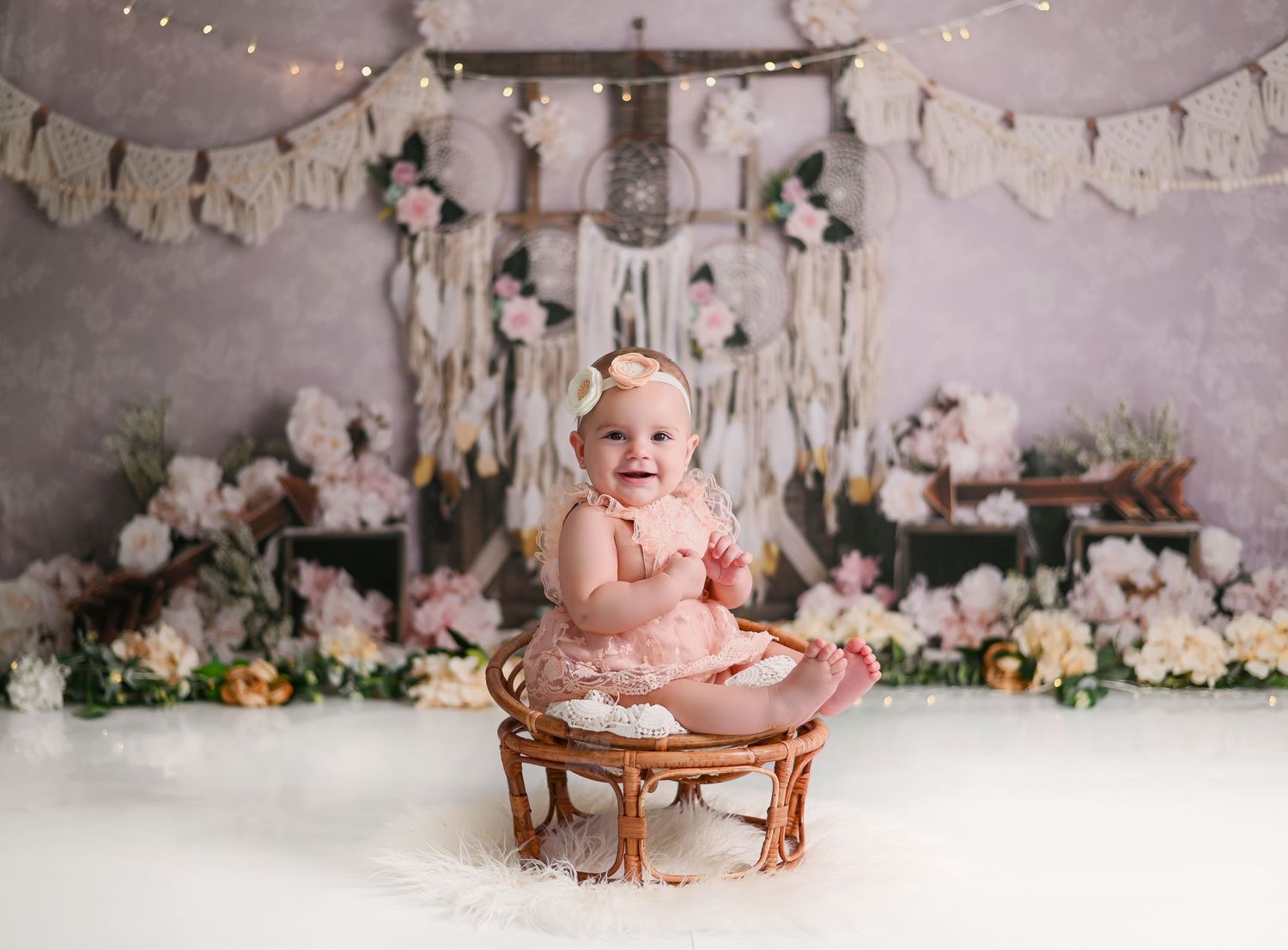 Studio portrait with vintage wicker chair, floral backdrop and festive bunting banner decorations.