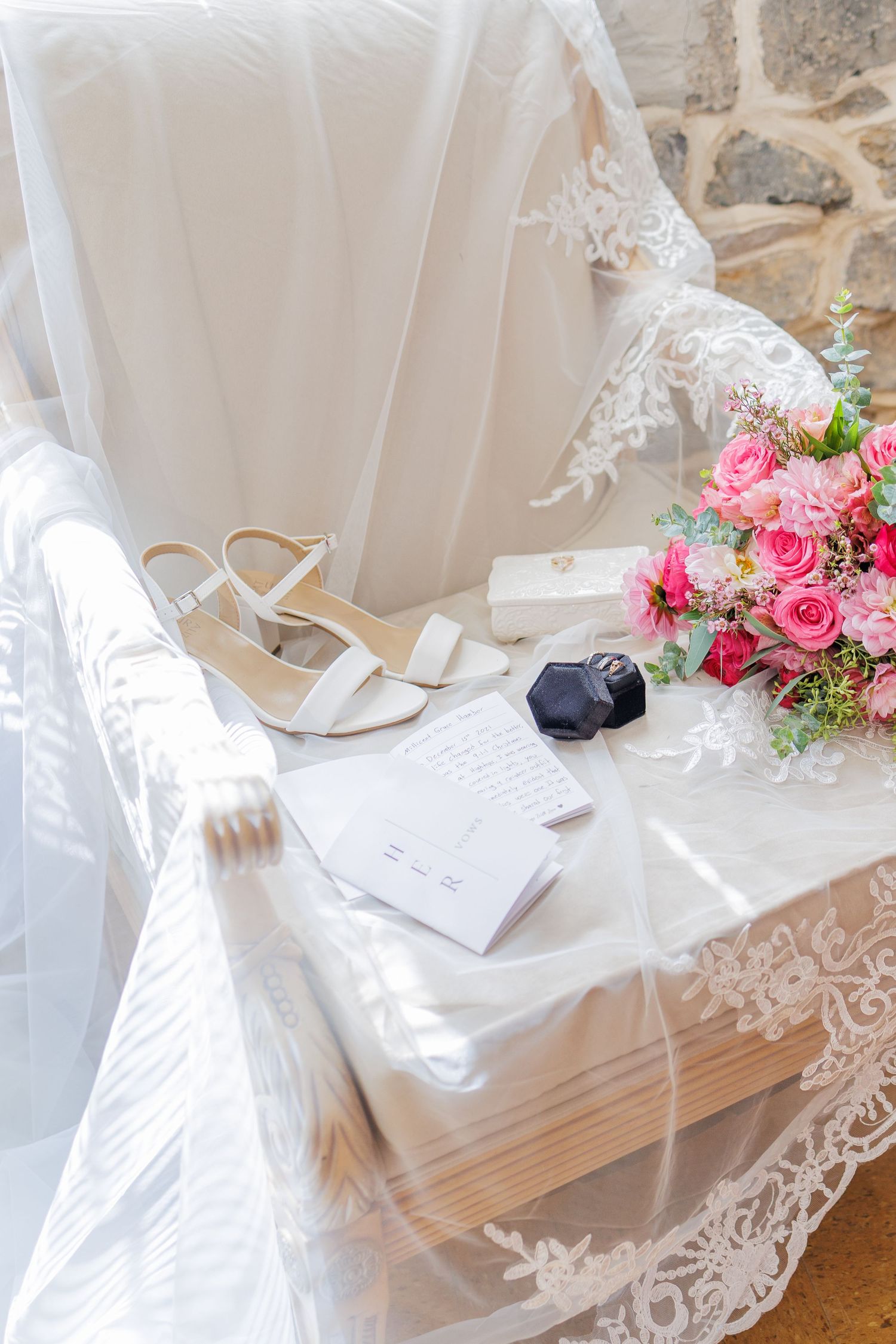 White lace and pink rose floral arrangements decorate a wedding ceremony setting with elegant seating.