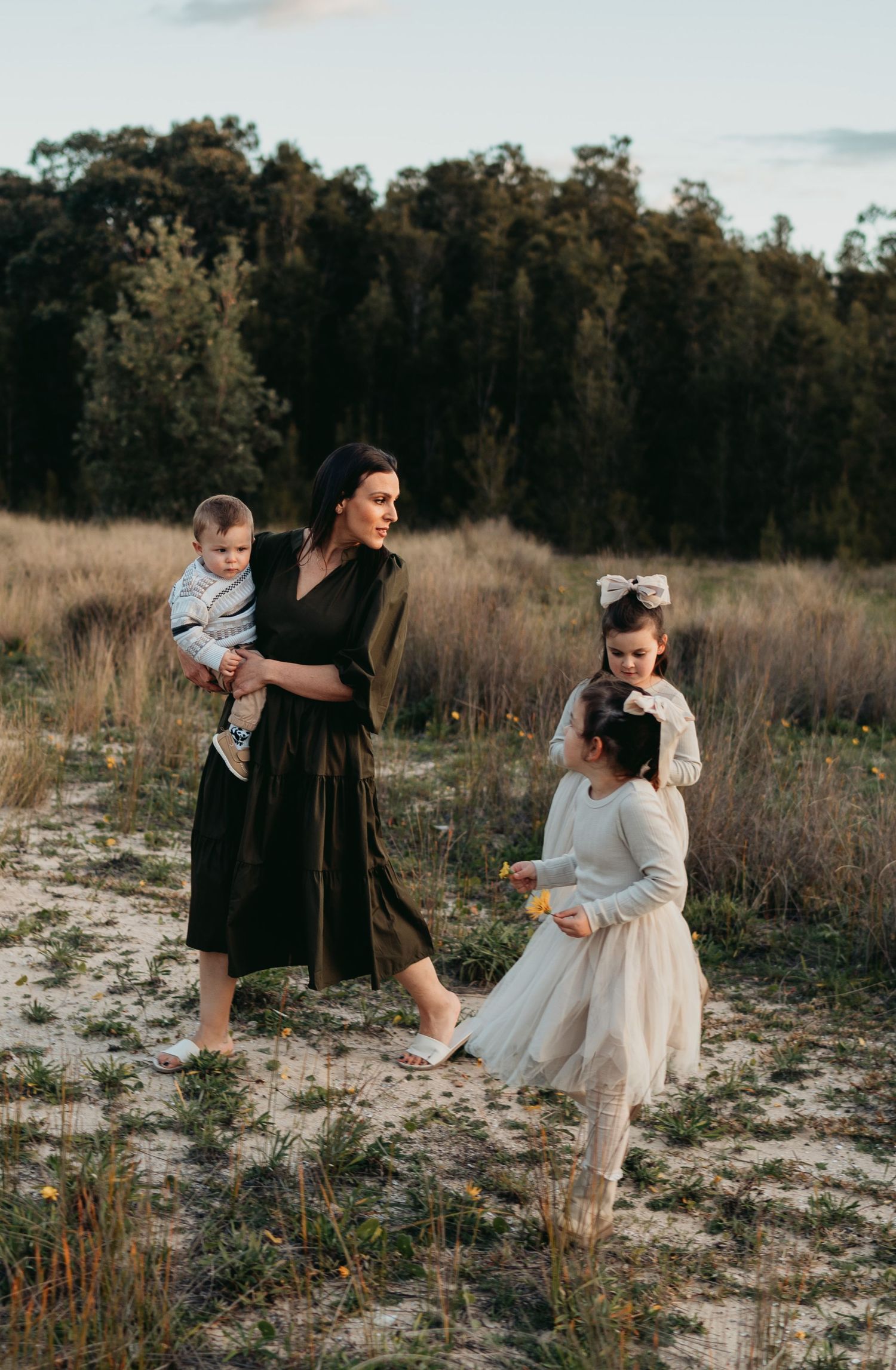 Family enjoying a casual stroll together in a rustic field at sunset.