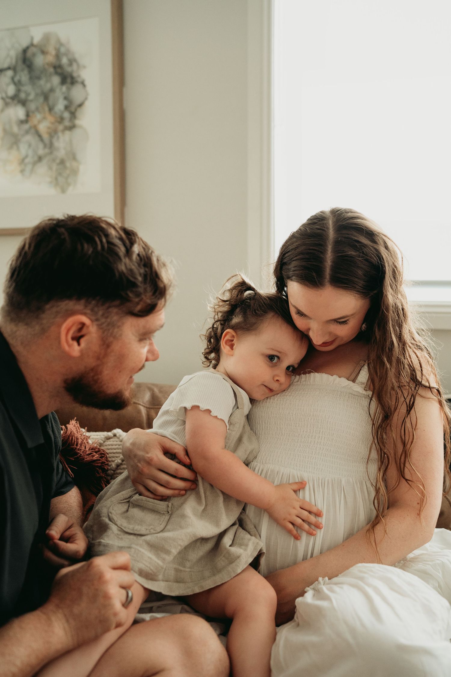 Intimate family moment captured in soft natural window light.