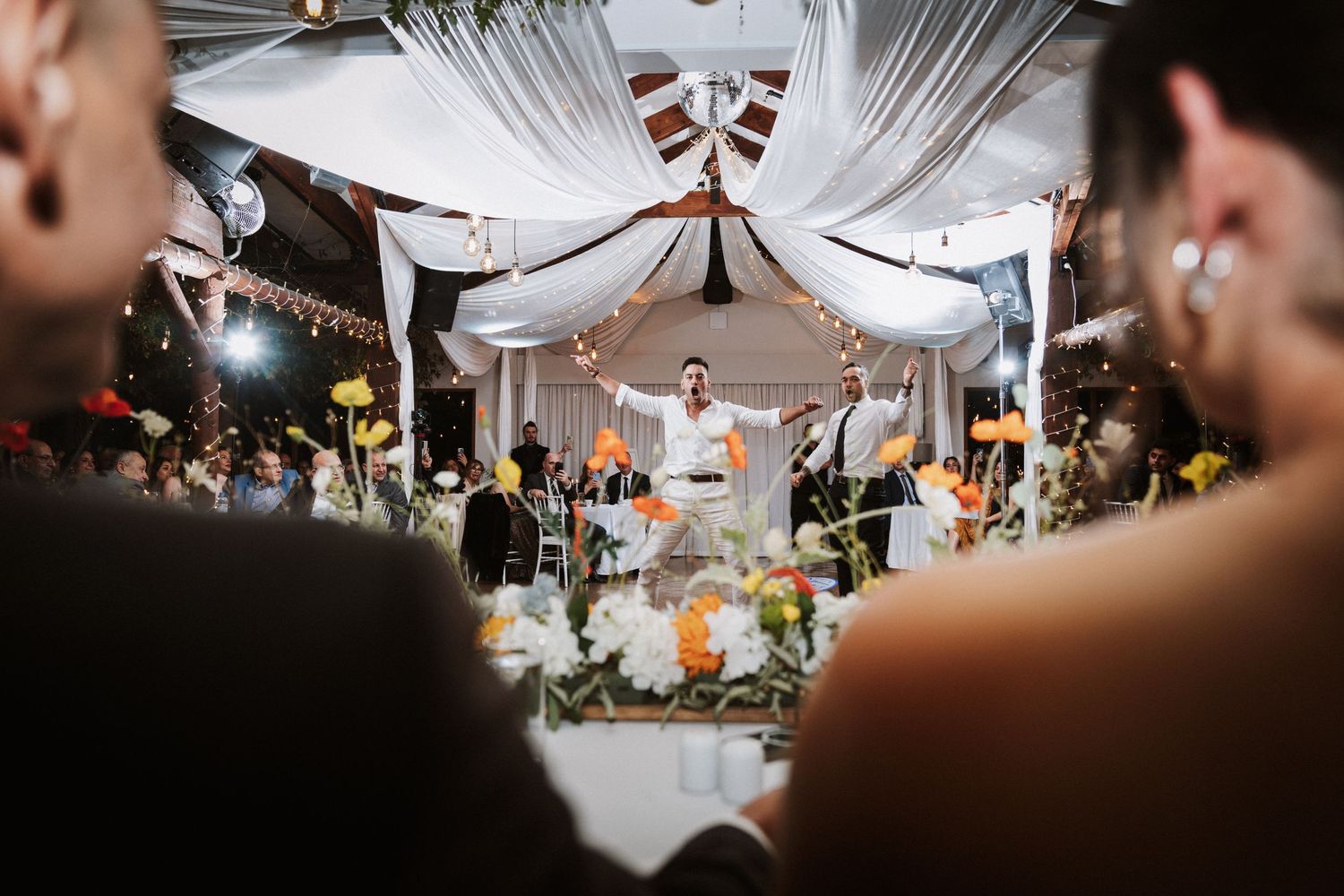 Elegant wedding reception under white draped tent with floral centerpieces and officiant at altar.