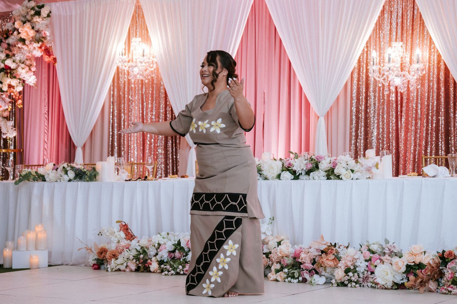 Woman in traditional gray and black dress poses gracefully at elegant wedding reception with pink floral decor.