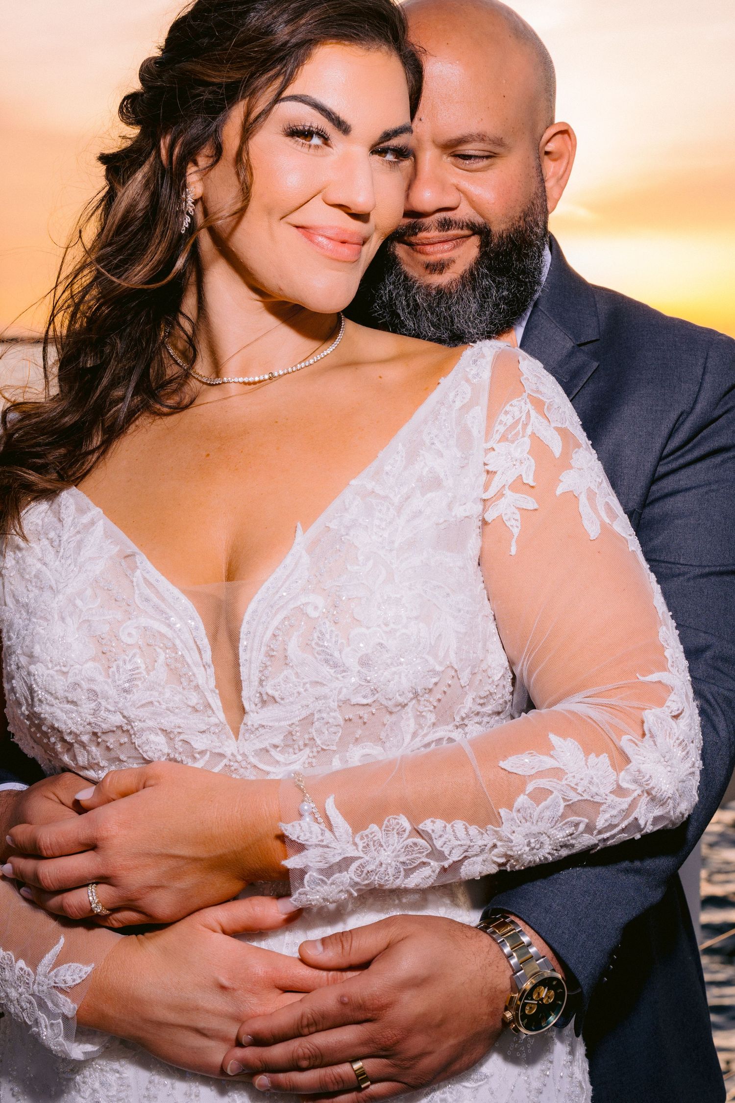 Romantic sunset wedding portrait of couple embracing, bride wearing lace long sleeve gown and groom in navy suit. Tampa Wedding Photographer