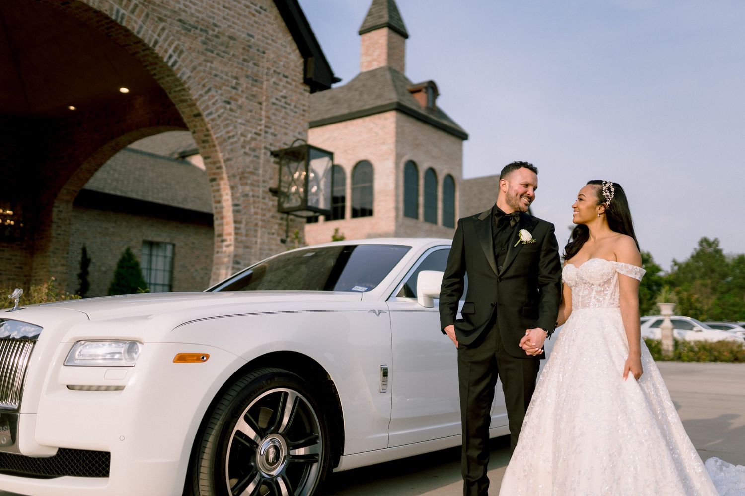 A line of elegant white luxury vehicles parked against a brick wall backdrop at a formal event. Tampa Bay Wedding Photographer
