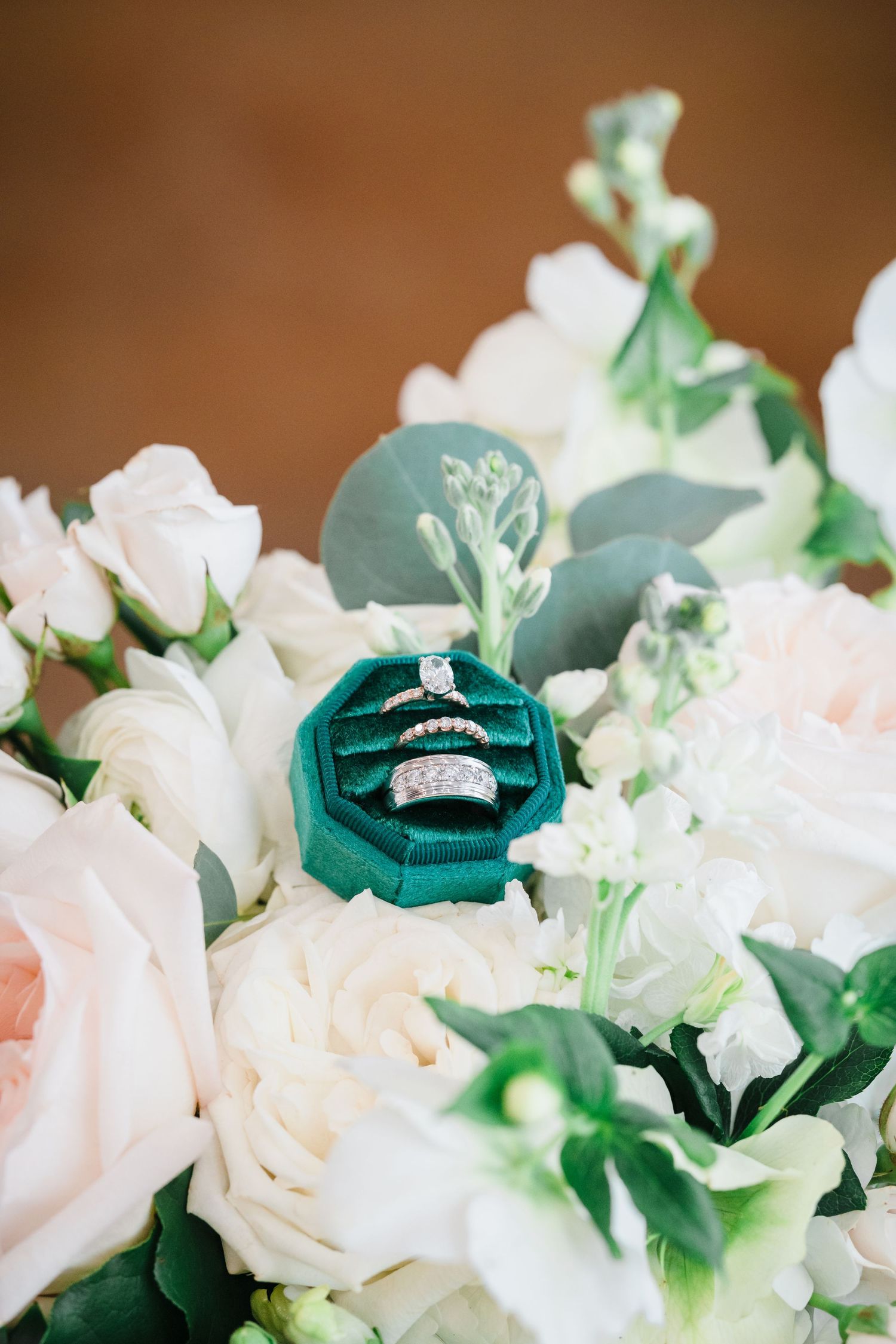 Wedding rings in an emerald green velvet box nestled among delicate white and pink roses. Tampa Bay Wedding Photographer