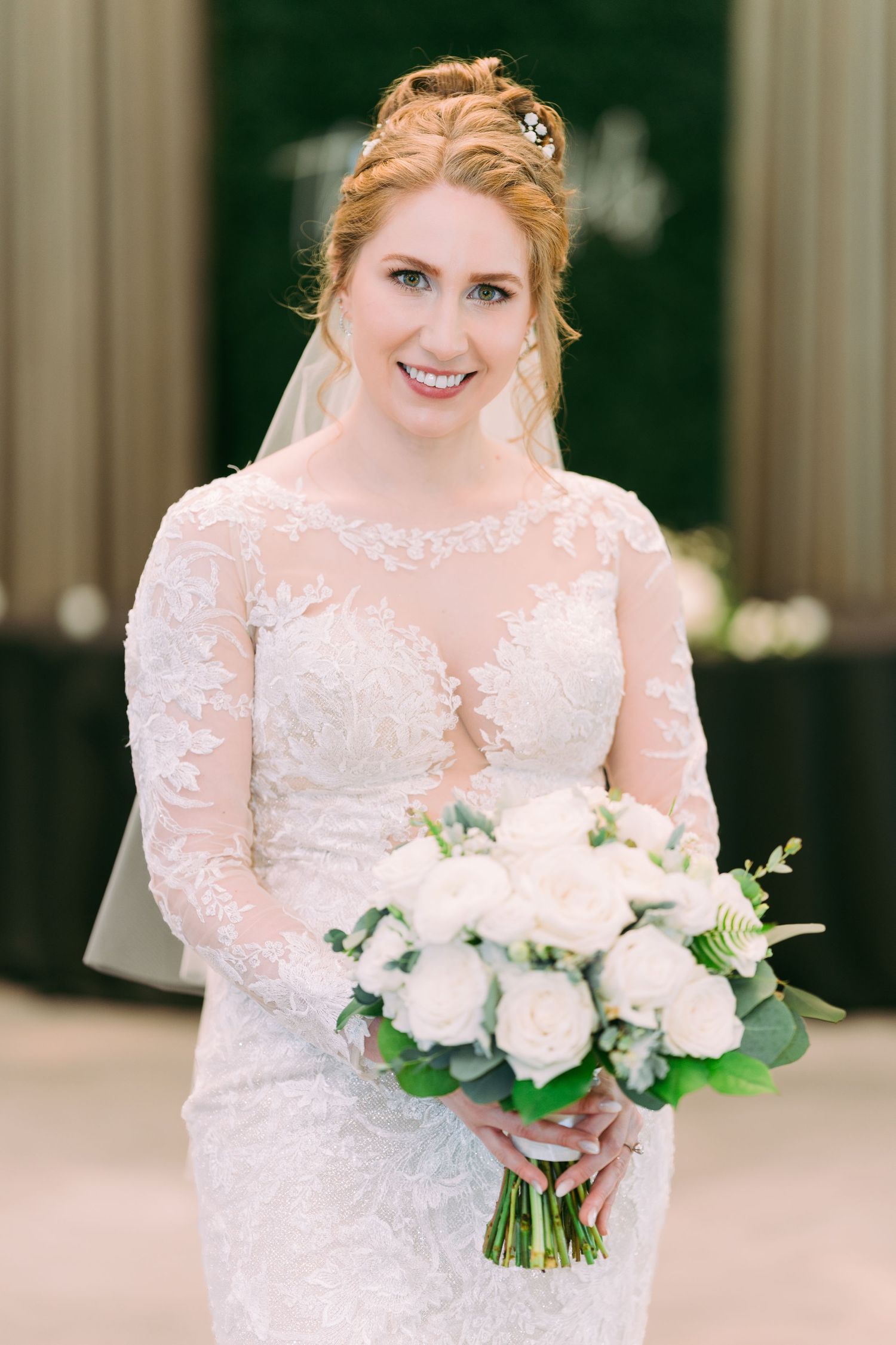 A bride in a long sleeve lace wedding gown holds a delicate pink and white rose bouquet with eucalyptus. Tampa Bay Wedding Photographer