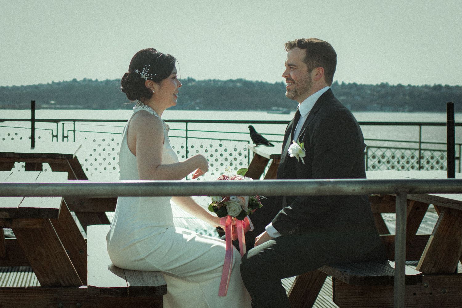 Bride and groom share a romantic moment at an outdoor Seattle waterfront venue during their wedding ceremony.