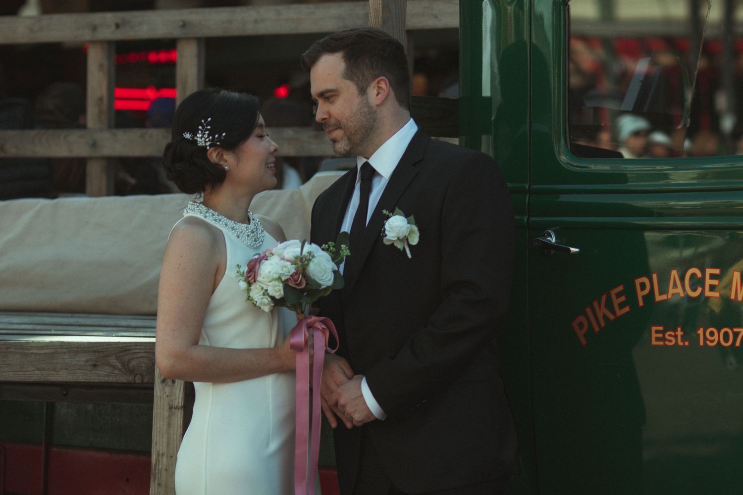 Bride and groom share a romantic moment near a vintage Pike Place Market truck in Seattle, WA.