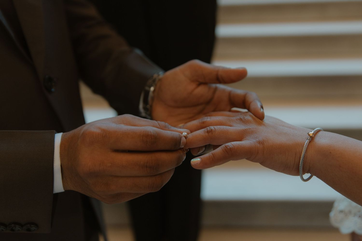 A close-up shot of hands exchanging rings during a ceremony.
