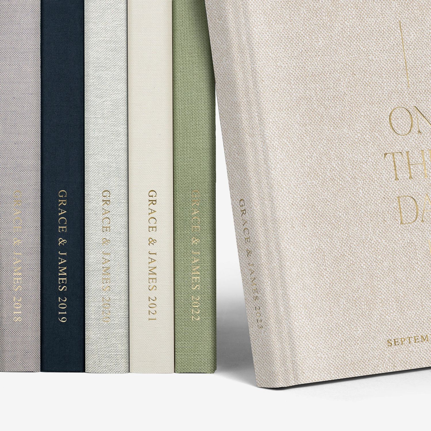 Row of elegant photo albums in neutral tones displayed on shelf.