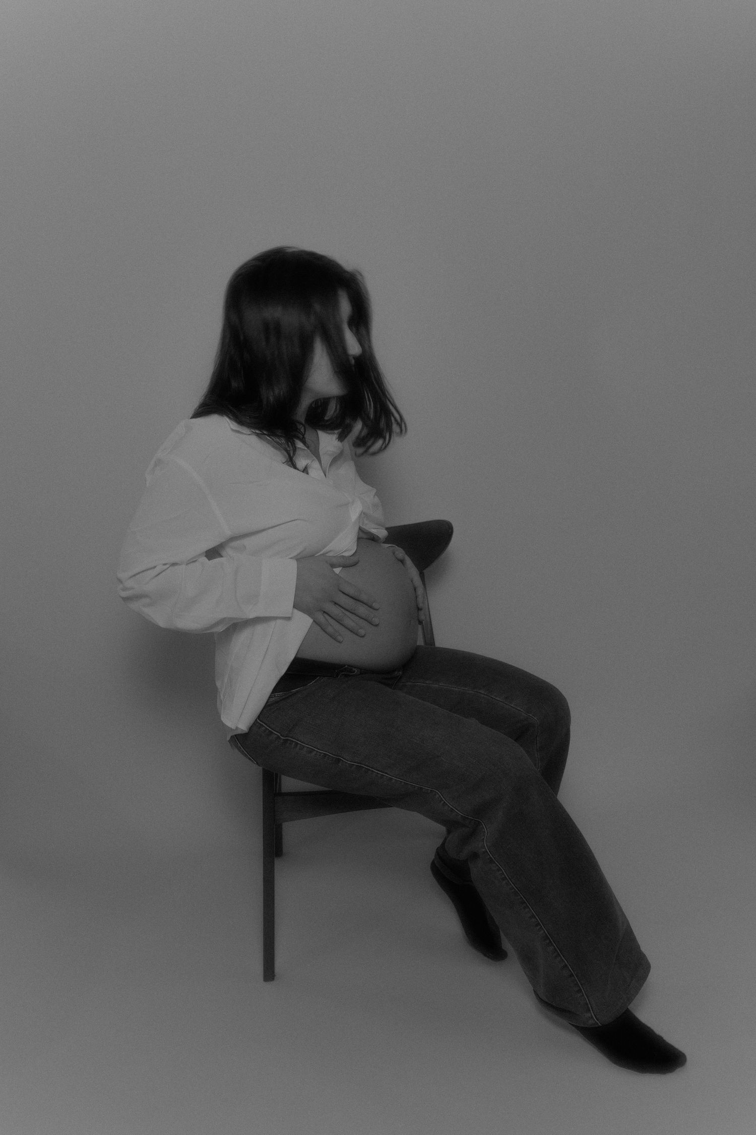 Moody grayscale portrait showing relaxed pose on chair.