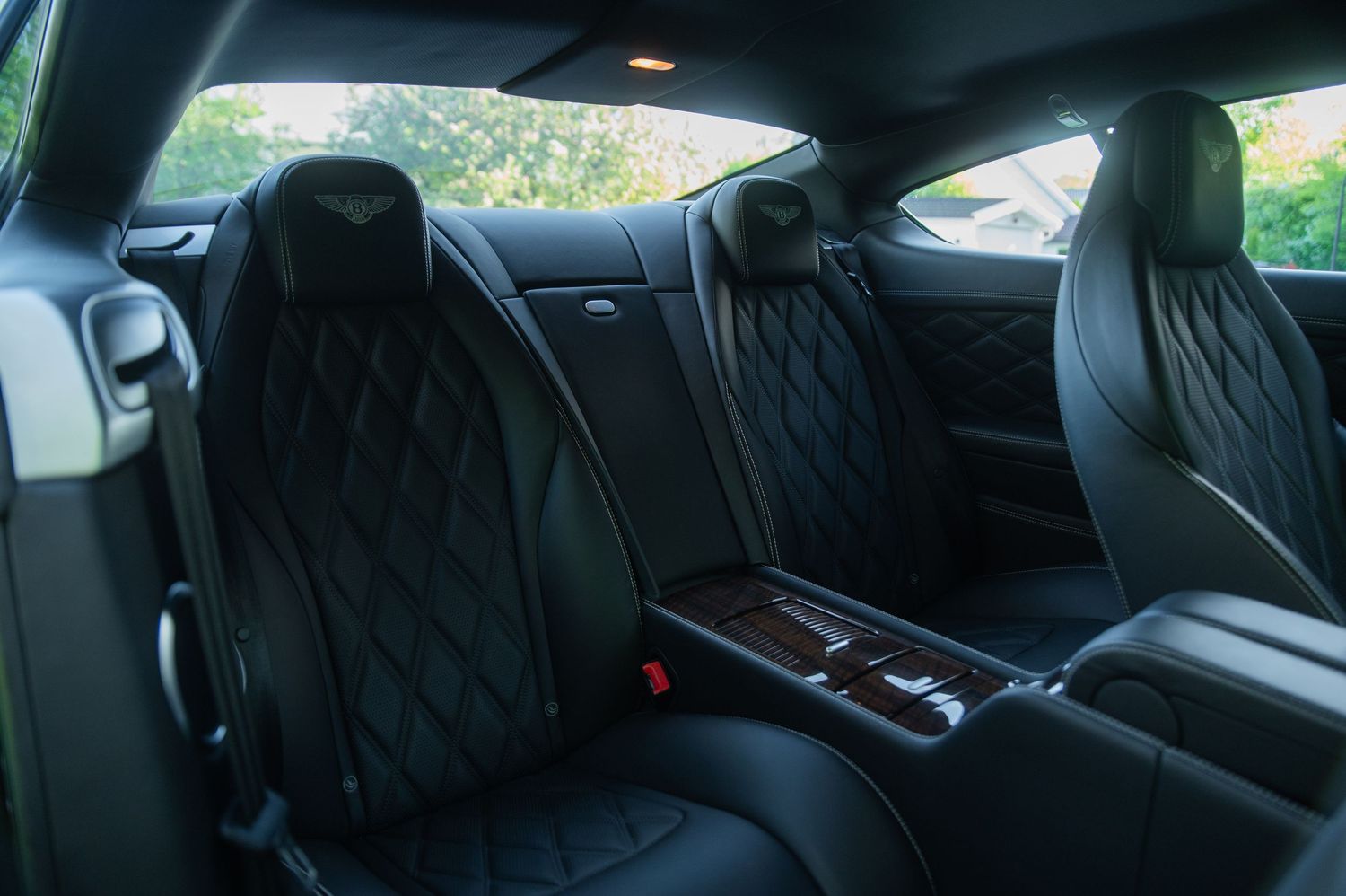 Premium quilted black leather rear seats of a Bentley Continental GT with wood trim accents.