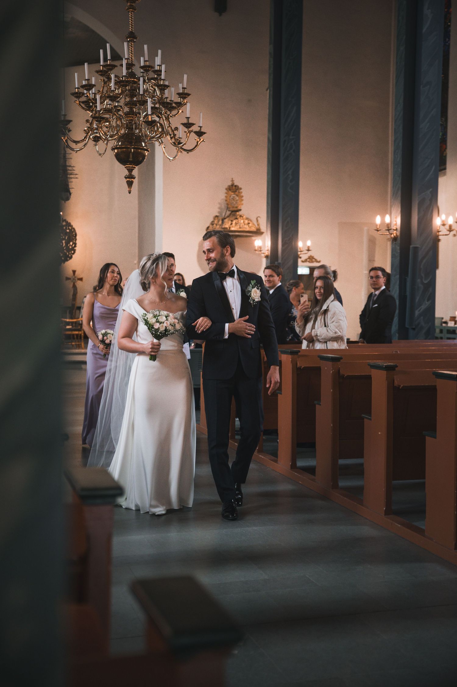 Bride and groom walking down the aisle of a candlelit church after their ceremony.