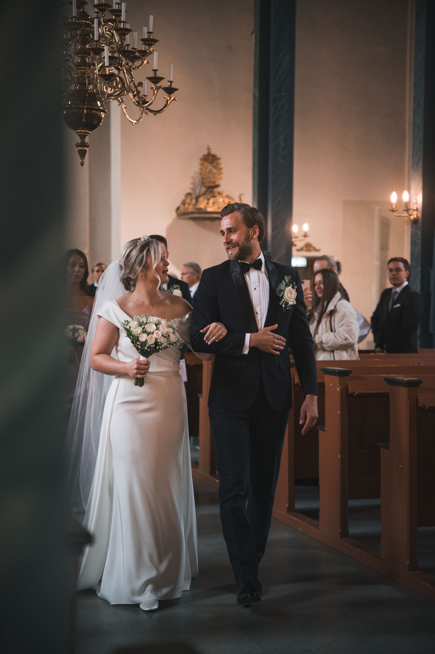Smiling bride and groom walking down the aisle of an elegant church after wedding.