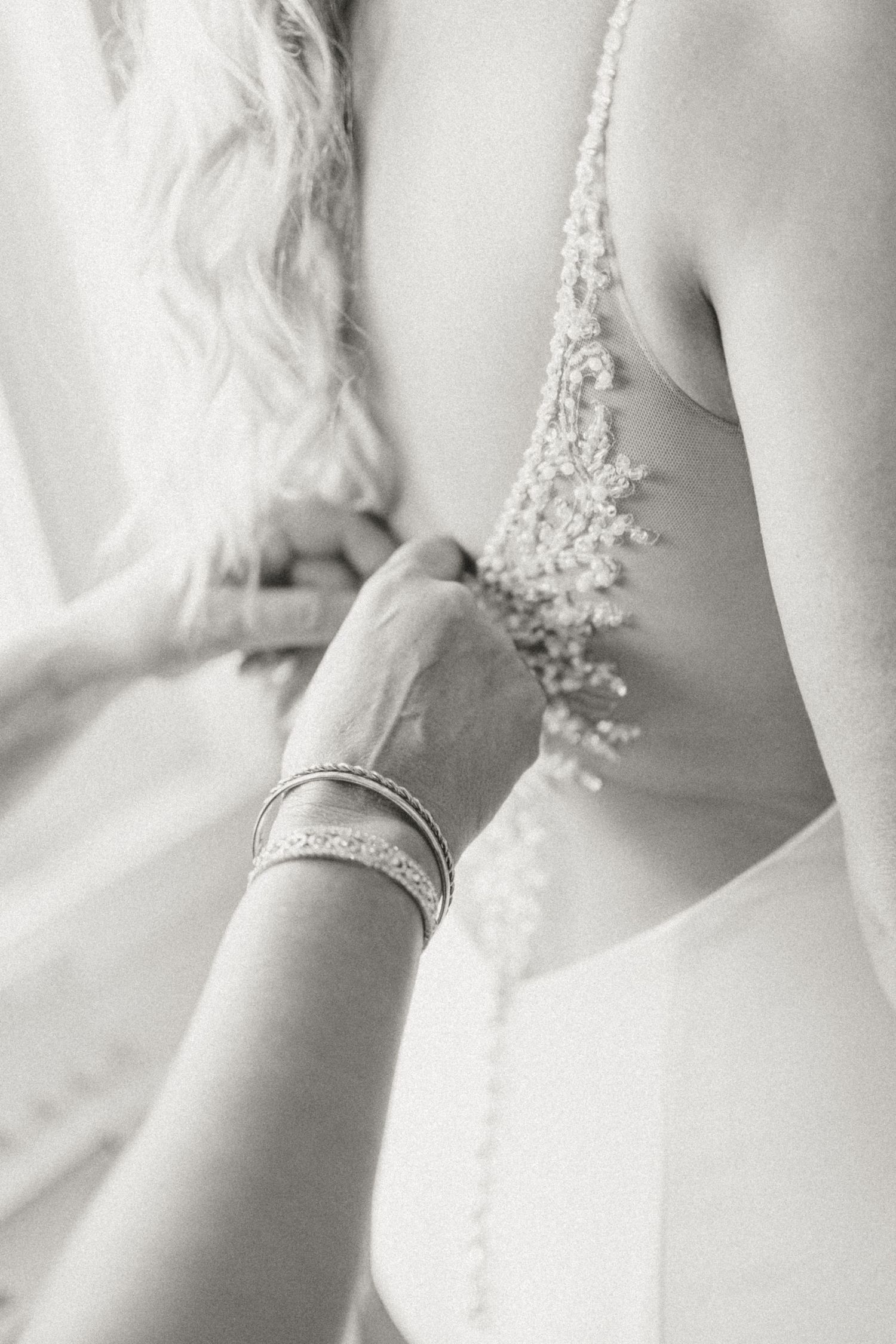 Close-up detail of delicate bridal jewelry and lace on a wedding dress.