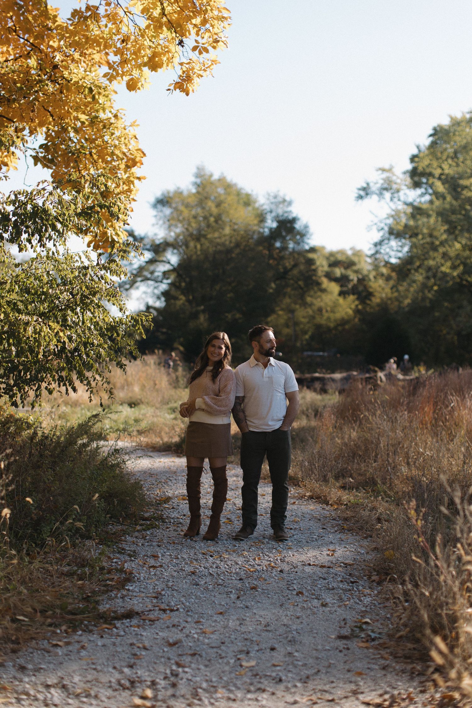 A couple strolling together on a gravel path during golden hour.