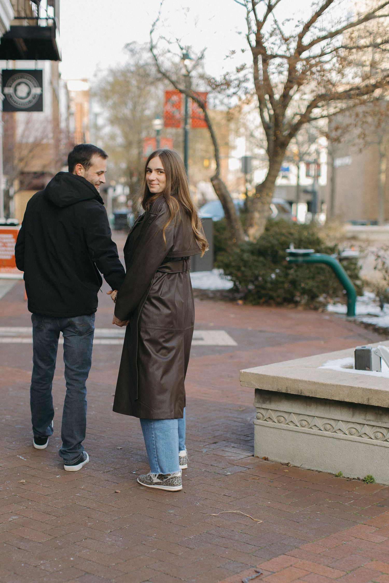 A couple walking together on a brick pathway during an autumn day.