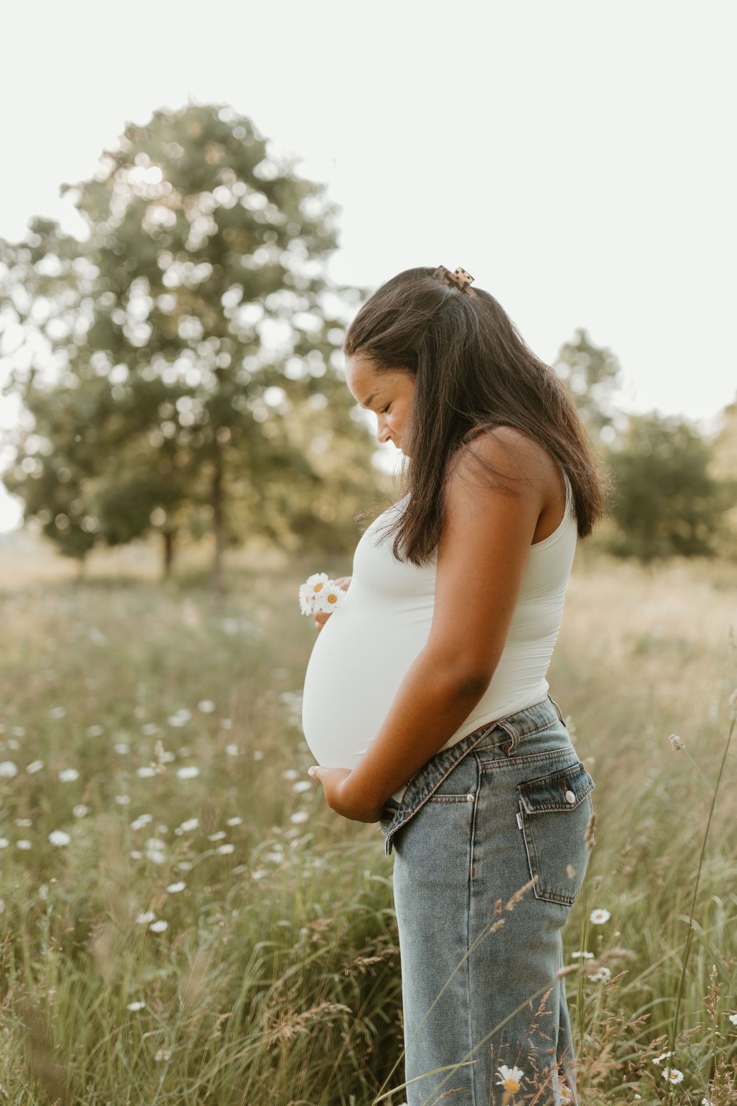 A couple shares an intimate moment in a field of wildflowers during a summer maternity session.